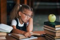 Bored and tired. Cute little girl with pigtails is in the library. Apple on the books Royalty Free Stock Photo