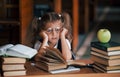 Bored and tired. Cute little girl with pigtails is in the library. Apple on the books Royalty Free Stock Photo