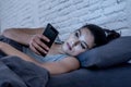 Bored and tired pretty young woman using mobile phone in bed. Royalty Free Stock Photo