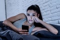 Bored and tired pretty young woman using mobile phone in bed. Royalty Free Stock Photo