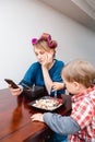 Bored tired white Caucasian young woman mother housewife with hair-curlers in hair looking on phone Royalty Free Stock Photo