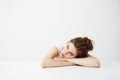 Bored tired young pretty girl with bun thinking dreaming lying on table over white background. Royalty Free Stock Photo