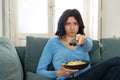 Bored woman changing TV channels with remote control