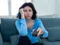 Bored woman changing TV channels with remote control