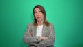 Bored woman in jacet posing with crossed arms and looking at the camera over green background