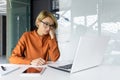 Bored woman working inside office at workplace, boring routine work in blonde business woman, using laptop while sitting Royalty Free Stock Photo