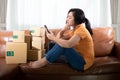 bored young Asia woman is sitting using a mobile phone on the sofa at her room Royalty Free Stock Photo