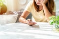 Bored young woman looking disappointed at her smart phone while waiting someone in restaurant Royalty Free Stock Photo