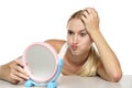 Bored young blond woman looking at herself in the mirror Royalty Free Stock Photo