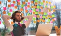 Bored young businessman sitting with laptop against window at office Royalty Free Stock Photo