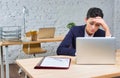 Bored young businesswoman sitting with laptop at desk against brick wall in office Royalty Free Stock Photo