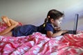 Bored young girl age 06 using a laptop in bedroom while forced to stay at home because government policies efforts to prevent Royalty Free Stock Photo