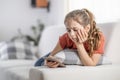 Bored young girl finds no more joy in scrolling on her phone as she sits at home on a couch Royalty Free Stock Photo