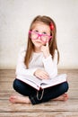 Bored young girl wearing glasses and holding a book Royalty Free Stock Photo