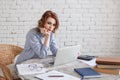 Bored young woman in the office working with a laptop and staring at computer screen. Royalty Free Stock Photo