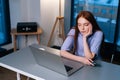 Bored young woman scrolling social networks at laptop sitting at desk in home office room near window. Royalty Free Stock Photo