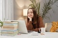 Bored young woman wearing brown sweater using laptop while working at home looking at computer screen with uninterest being boring Royalty Free Stock Photo
