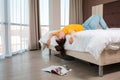 Boredom. A young woman is lying on the bed, her head and hands hanging over the edge. There`s a magazine on the floor. Home Royalty Free Stock Photo