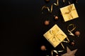 Borfer from gift boxes wrapped golden paper and ribbon decorated streamers and baubles on black background. Top view. Flat lay.