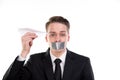 Boring businessman with tape on his mouth hold a paper plane in hand Royalty Free Stock Photo