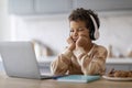 Boring Content. Upset little black boy in headphones looking at laptop screen Royalty Free Stock Photo