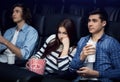 Boring date. Unhappy young girl with boyfriend watching film in movie theater Royalty Free Stock Photo