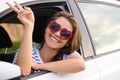 Boring days behind me, brighter days ahead. a young woman wearing showing a peace sign out of a car window on a road Royalty Free Stock Photo