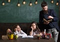 Boring lesson concept. Man with beard teaches schoolgirls, reading book. Bored and tired children listening teacher