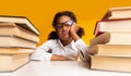 Discontented Black Schoolgirl Sitting At Books Over Yellow Background, Studio