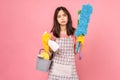 woman wearing apron with yellow rubber gloves and holding bucket of cleaning supplies on pink background. Royalty Free Stock Photo