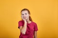 Boring young lady in red shirt keeping hand on chin, thinking about issue