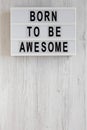 `Born to be awesome` words on a modern board on a white wooden background, top view. Overhead, from above, flat lay. Copy space