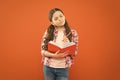 Born to read. Adorable little girl learning to read and write on orange background. Cute small child can read a book