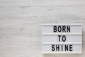 `Born to shine` words on a modern board on a white wooden surface, top view. Overhead, from above, flat lay. Space for text