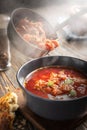 Borsch is poured into a bowl from a ladle from which steam, a traditional Ukrainian vegetable soup made from beets