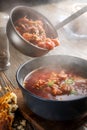 Borsch is poured into a bowl from a ladle from which steam, a traditional Ukrainian vegetable soup made from beets