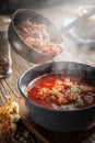 Borsch is poured into a bowl from a ladle from which steam, a traditional Ukrainian vegetable soup made from beets Royalty Free Stock Photo