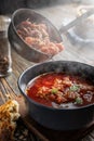 Borsch is poured into a bowl from a ladle from which steam, a traditional Ukrainian vegetable soup made from beets