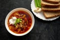 Borscht soup in a white bowl with black bread, green onion and garlic on dark gray background. Famous traditional Ukrainian and Ru Royalty Free Stock Photo