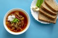 Borscht soup in a white bowl with brown bread, green onion and garlic on blue background. Famous traditional Ukrainian and Russian Royalty Free Stock Photo