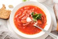 Borscht with sour cream and herbs in a white plate,  bread, spoon on a  wooden table top view Royalty Free Stock Photo