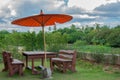Borwn chairs and orange umbrella in garden Royalty Free Stock Photo