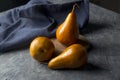 Bosc pear in yellow tone, which is distinguished by its elongated shape. These pears are on a gray wooden board and accompanied by Royalty Free Stock Photo