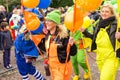 Cheerful lady in orange overall with green hat holds a stick with orange balloons