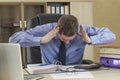 Boss businessman at his desk in the office with a pile of folders. Holds his head with his hands bending over the folder. The Royalty Free Stock Photo