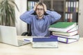 Boss businessman at his desk in the office with a pile of folders. Holds his head with his hands. The manager is not doing the job Royalty Free Stock Photo