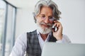 Boss in formal clothes works in office. Senior stylish modern man with grey hair and beard indoors