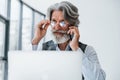 Boss in formal clothes works in office. Senior stylish modern man with grey hair and beard indoors