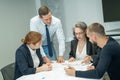 The boss gives instructions to three employees in the office conference room. Brainstorming engineers and architects.