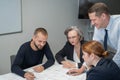 The boss gives instructions to three employees in the office conference room. Brainstorming engineers and architects.